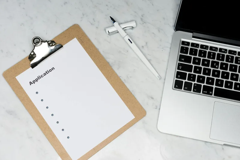Business registration application form with laptop and pen on office desk
